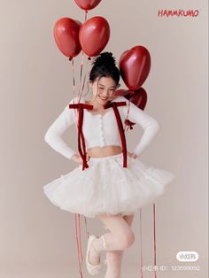 a girl in a tutu and skirt with red balloons on her head is posing for the camera