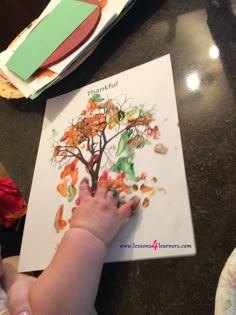 a baby is playing with an autumn tree book