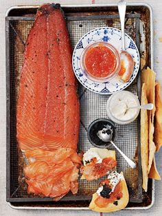 an assortment of food on a tray including fish, crackers and sauces