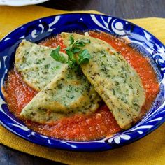 two pieces of bread on top of tomato sauce in a blue and white bowl with yellow napkin