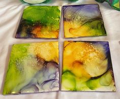 four square glass coasters sitting on top of a white table next to a vase