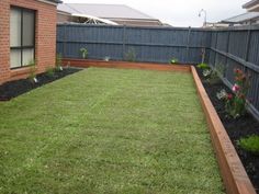 an empty backyard with grass and flowers in it