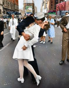 a man and woman are kissing in the middle of a street while people walk by