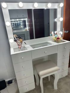 a white vanity with lights and stools in front of the mirror on the wall