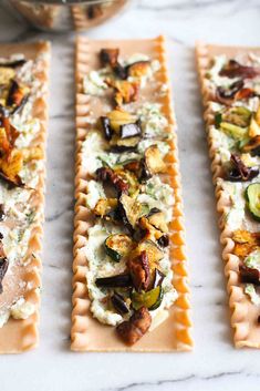 three crackers with different toppings on them sitting on a marble counter top next to a bowl