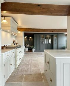 a large kitchen with white cabinets and counter tops in an open floor plan that has wood beams on the ceiling