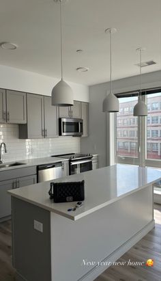 an empty kitchen with stainless steel appliances and white counter tops in front of a large window