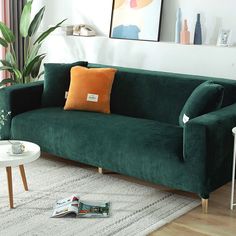 a living room with green velvet couches and white coffee table in front of it