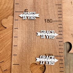 three wooden rulers with hearts and arrows on them, one measuring the distance between two pieces of wood