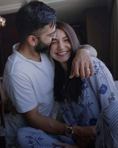 a man and woman cuddle together in pajamas