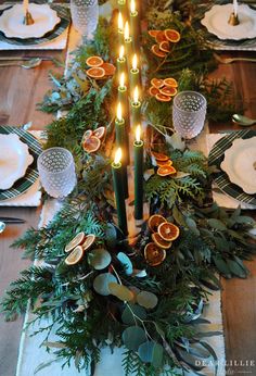 the table is set with candles and greenery for an elegant touch to the place setting