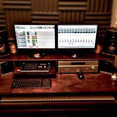 two computer monitors sitting next to each other on a wooden desk in front of speakers