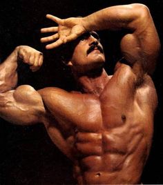 a man flexing his muscles in front of a black background