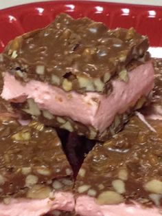 several pieces of chocolate and nuts on a red plate with pink frosting in the middle