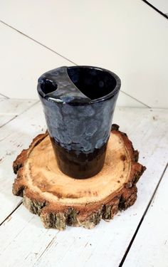 a black cup sitting on top of a tree stump