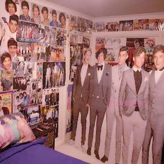 a group of young men standing next to each other in front of a wall full of pictures