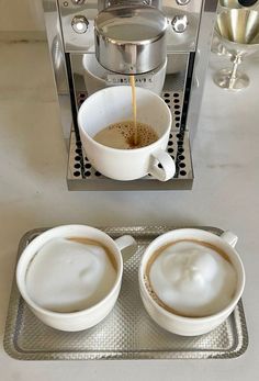 two cups of coffee being filled with liquid