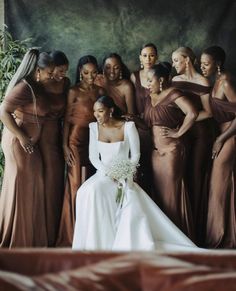 a group of women standing next to each other in front of a green wall wearing brown dresses