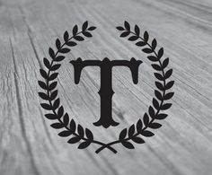 the letter t is surrounded by a laurel wreath on top of a wooden table,