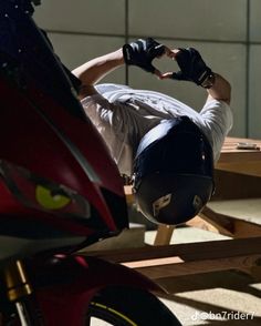 a man laying on top of a wooden table next to a red motorbike