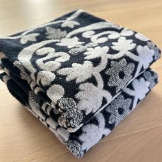 two black and white towels sitting on top of a wooden table next to each other