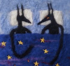 two black cats sitting on top of a blue surface with stars in the sky behind them