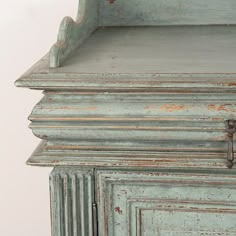 an old blue cabinet with a cross on the top and drawer doors, painted green