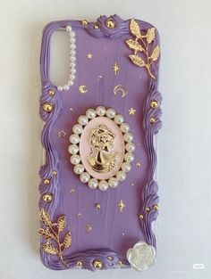 a cell phone case with pearls and a golden brooch sitting on top of it