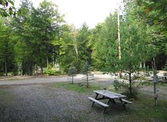 an empty picnic table in the middle of a park with lots of trees around it