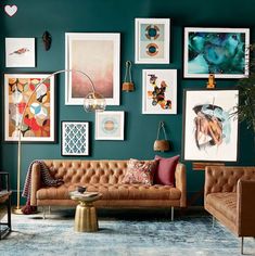 a living room with blue walls and pictures on the wall above the couch, coffee table