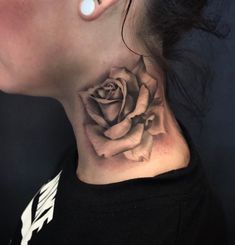 a woman's neck with a rose tattoo on it