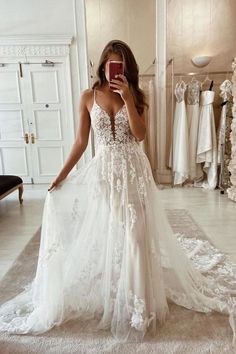 a woman in a wedding dress taking a selfie while looking at her cell phone