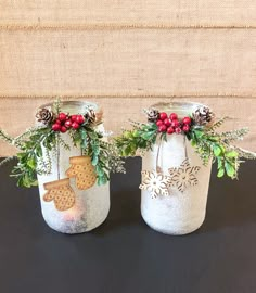 two mason jars decorated with christmas decorations and pine cones