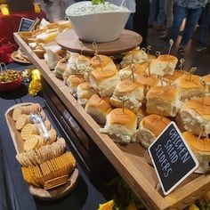 a table filled with lots of sandwiches and crackers next to bowls of dips