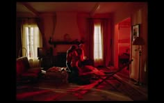 two people sitting in a room with red light coming through the windows