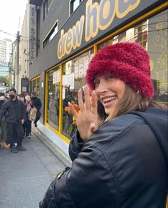 a woman with her hand up in front of a store