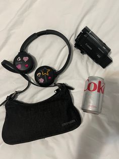 the contents of a purse, headphones and camera are laid out on a bed