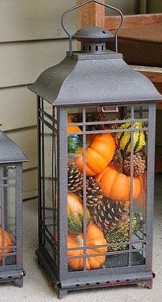 a lantern filled with pumpkins and pine cones