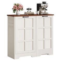 a white cabinet with two doors and some pink flowers on the top shelf next to it