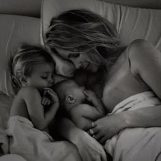 a woman and two small children laying in bed