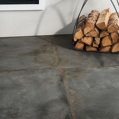 a pile of firewood sitting on top of a floor next to a white wall