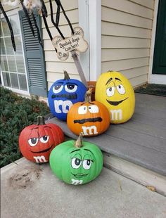 four pumpkins with faces painted on them sitting on the front step of a house