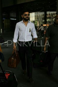 a man walking through an airport with his suitcases in hand and another person carrying luggage behind him