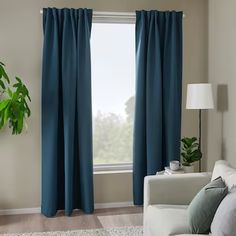 a living room with blue curtains and a white couch in front of a large window