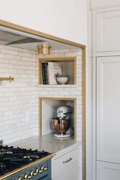 a kitchen with white brick walls and gold trim on the hood, stove top and cabinets