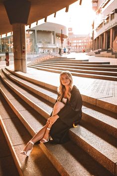 a woman is sitting on some steps in front of the building and smiling at the camera