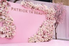 a pink display with flowers and butterflies on the wall at patrick ta beauty's show