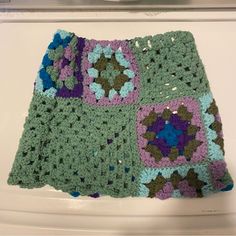 there is a crocheted granny blanket on the table with it's edges folded down