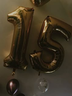 the number twenty five is made out of gold foil balloons and sits next to some chocolate candies