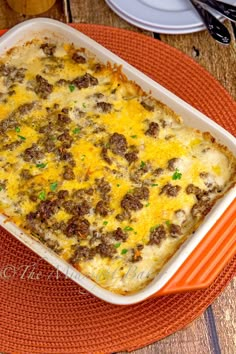 a casserole dish with meat and cheese in it on an orange place mat